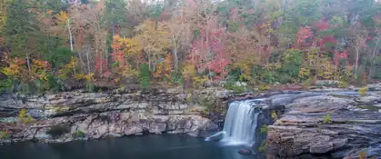 Waterfall pouring over sandstone ledges among fall color at Little River Canyon, Alabama