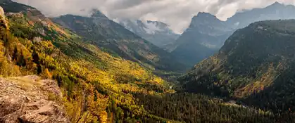Autumn-colored mountain valley under cloudy peaks in Glacier National Park, Montana