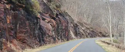 Blue Ridge Parkway curving past a rock cut and bare winter trees, North Carolina