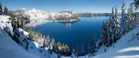 Deep blue Crater Lake ringed by snowy cliffs in winter, Oregon